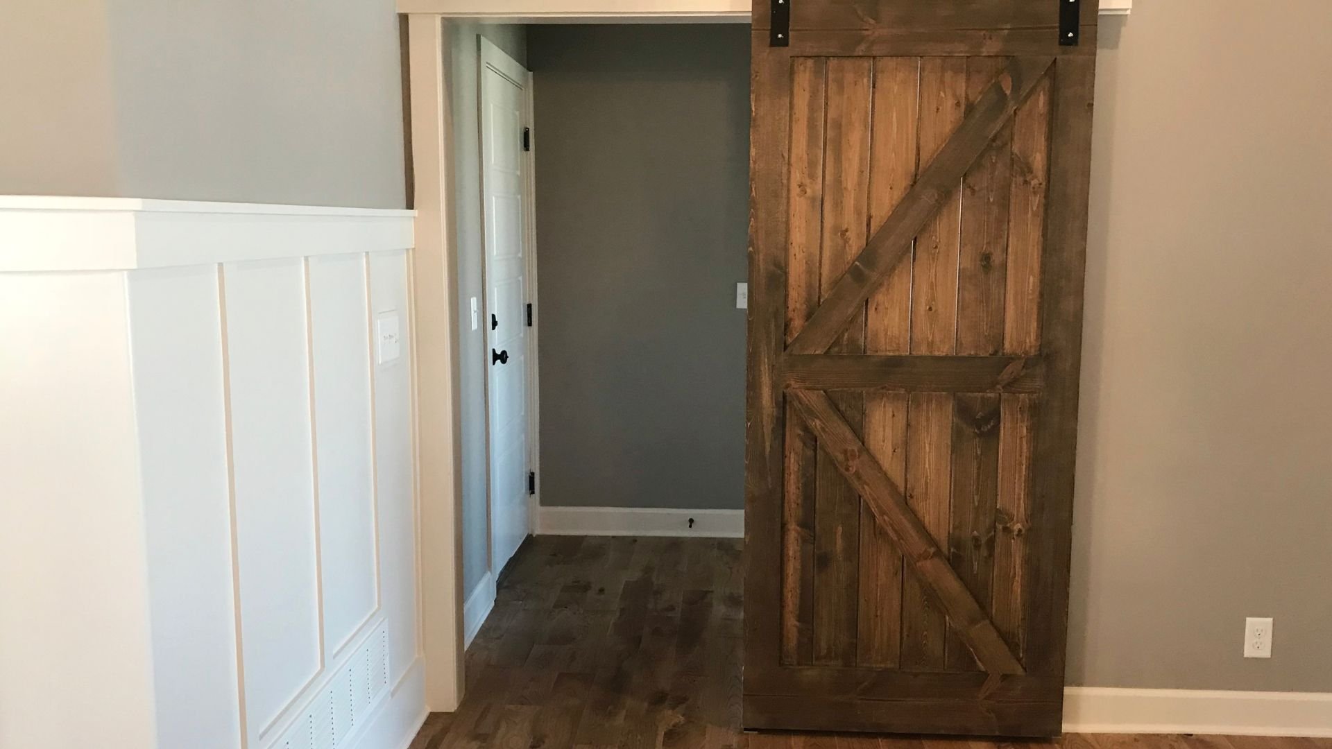 Rustic wooden barn door on sliding track in modern interior hallway