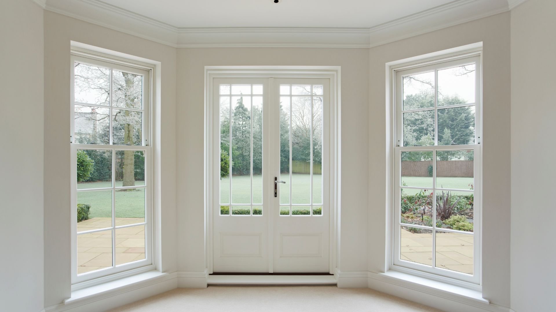 White interior with French doors and windows overlooking a green garden