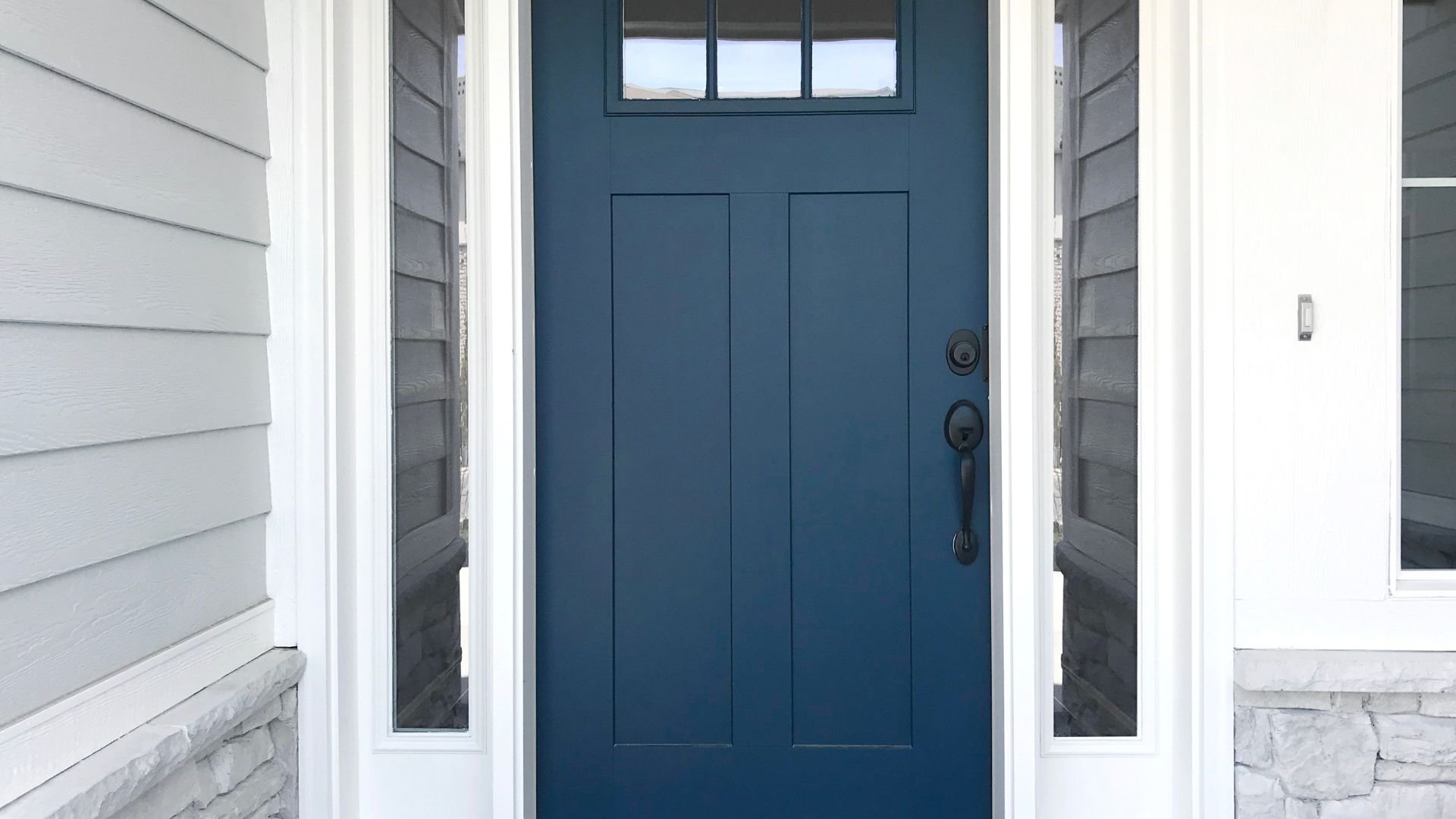 Blue front door with small windows on white house exterior