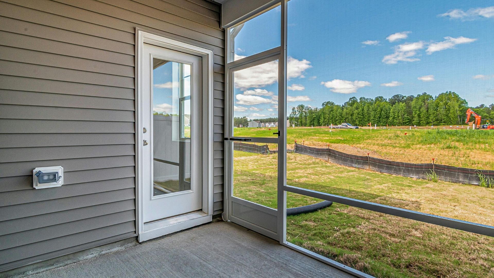 Open patio door with view of green field and construction site